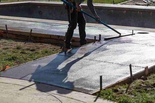 Concrete driveway installation with a worker smoothing freshly poured surface using a finishing tool in Parma Heights, OH