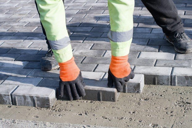 Concrete contractor placing brick pavers by hand for residential driveway installation in Columbia Station, OH