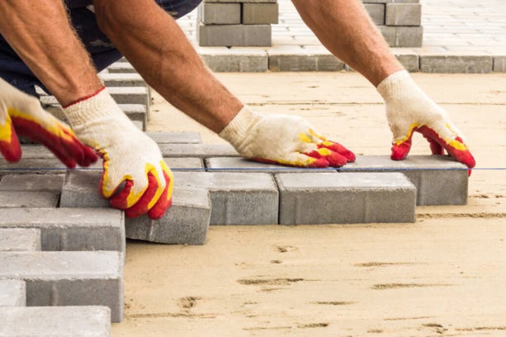 Contractor installing concrete pavers for patio construction on a leveled sand base in Parma Heights, OH