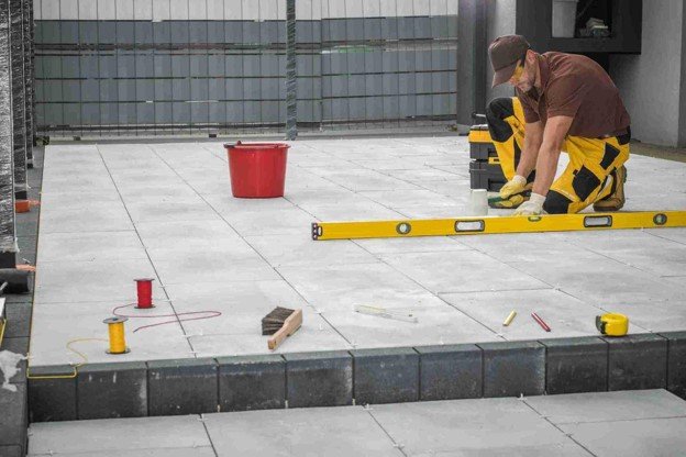Contractor using a level tool to align large concrete patio slabs during installation in Columbia Station, OH